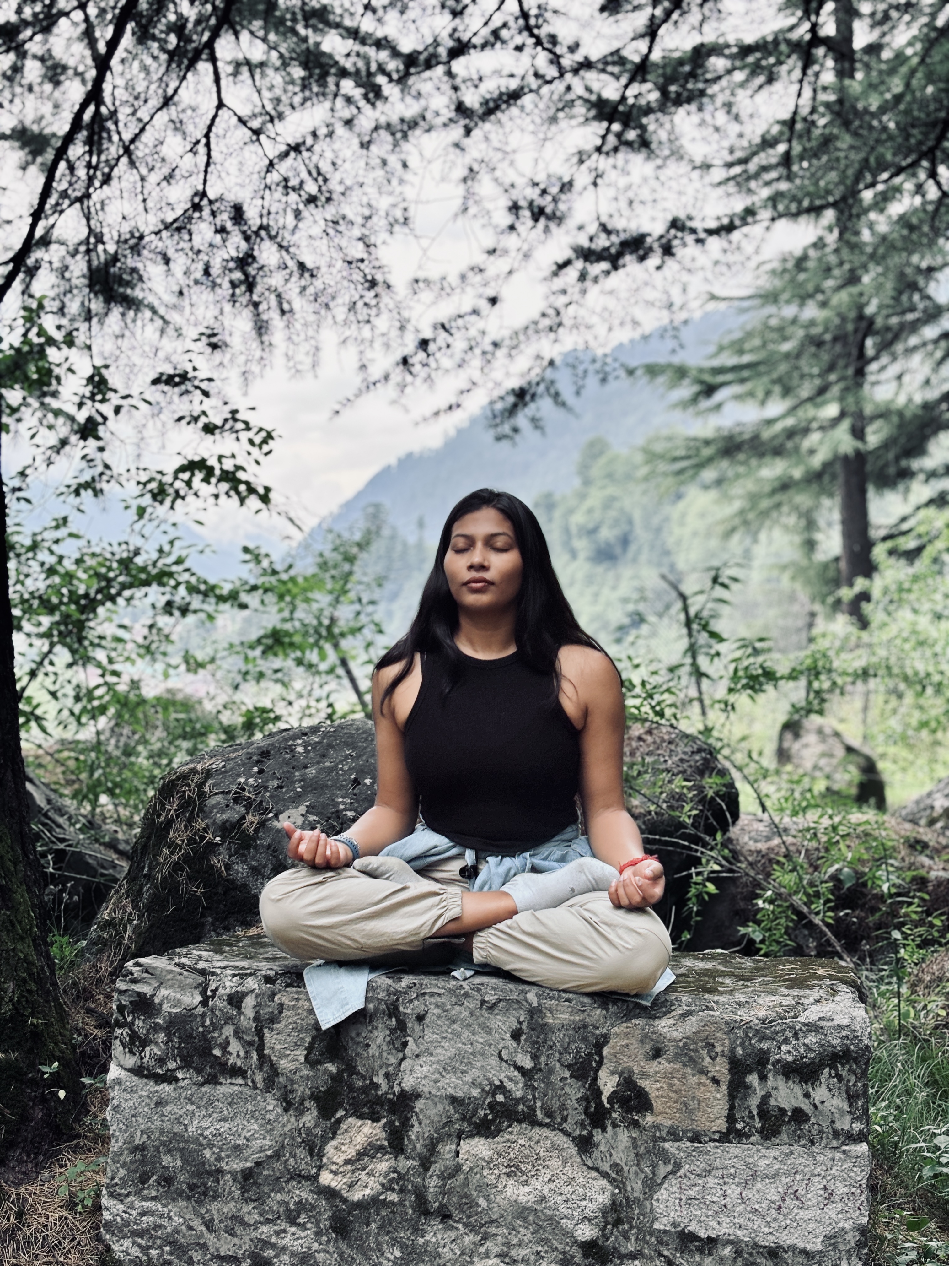 Purnima seated in meditation with chin mudra in a tranquil mountain forest